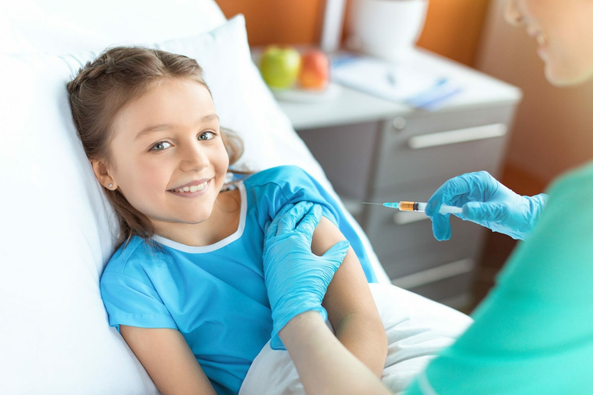 A young girl receiving an injection from a pediatrician in a Sugar Land hospital bed.