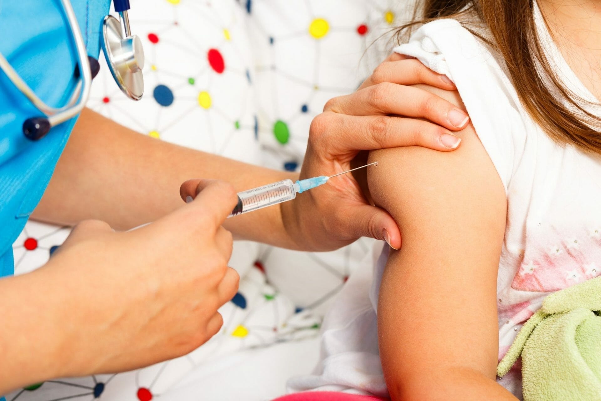 A young girl receiving an injection from a pediatrician.