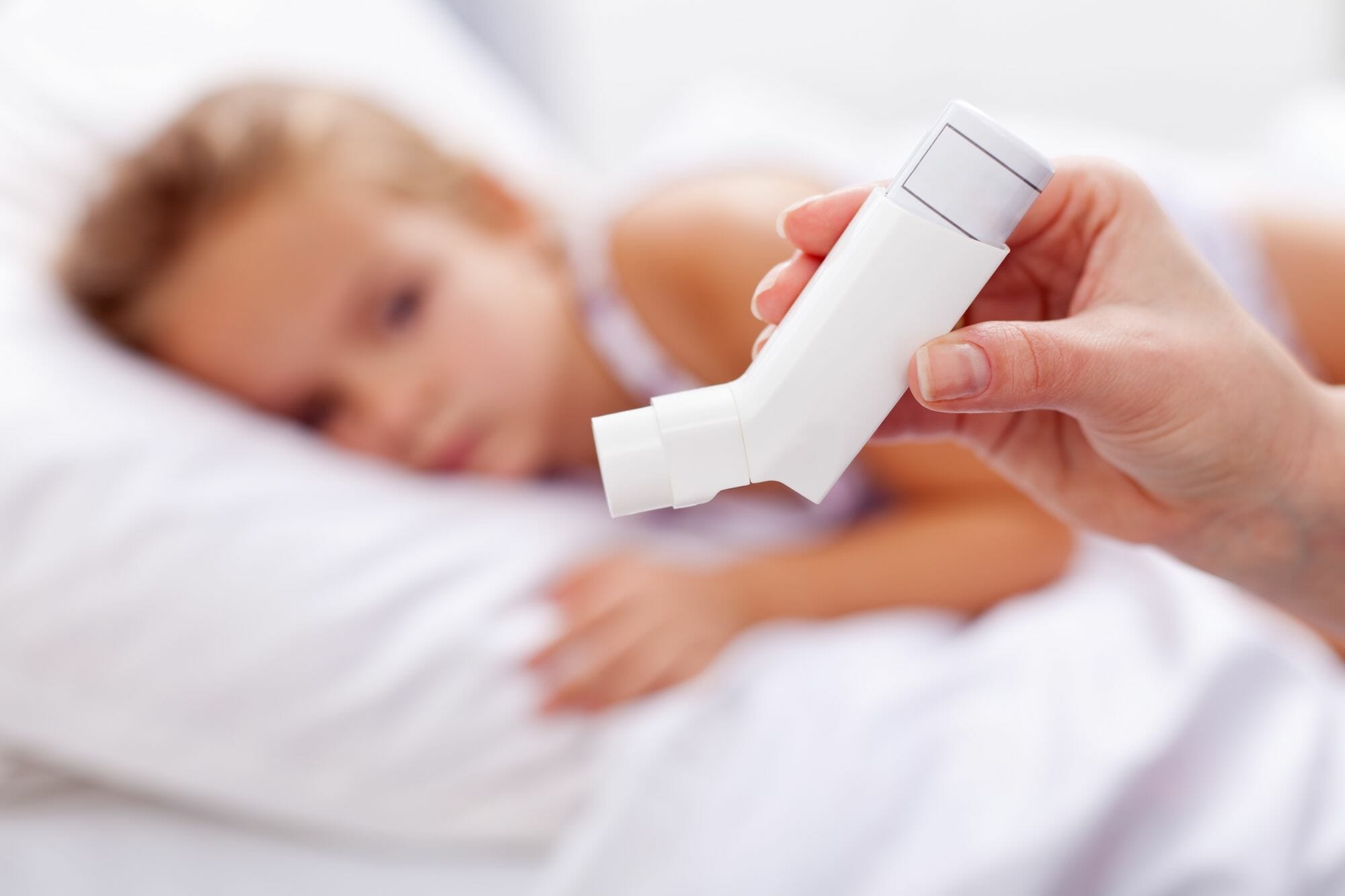 A little girl is holding an inhaler in bed in Sugar Land.